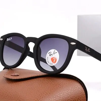 One pair of round black-framed sunglasses resting on a tan leather case