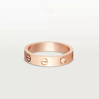 A single rose-gold band ring with a screw-head pattern on a plain white surface