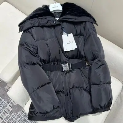 A glossy black quilted puffer jacket photographed alone on a pale textile surface