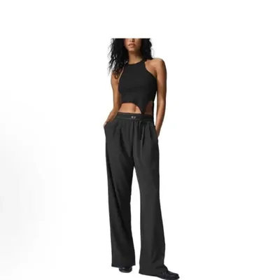 A studio shot of a model in a black cropped tank and wide-leg grey trousers against white